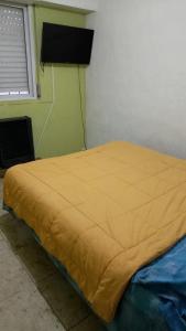 uma cama num quarto com um cobertor amarelo em apartamento los lobos em Mar del Plata