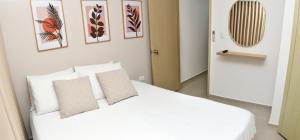 a bedroom with a bed with white sheets and pillows at Excelente ubicación y cómodo apto, perfecto para ti! in Barranquilla