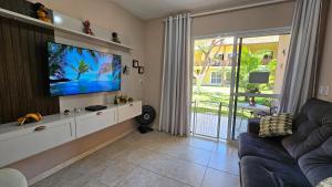 a living room with a flat screen tv and a couch at Arembepe - Aldeia St Sebastien Casa Mar 10 in Camaçari