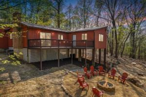 eine rote Hütte im Wald mit einer Terrasse und Stühlen in der Unterkunft Relaxing 2-Master Suite Mountain Top - Fire Pit in New Market