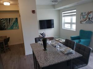 a living room with a table and chairs and a television at Luxurious Condo Apartment 1BR-1BA-1Office free parking in Brampton