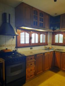 uma cozinha com armários de madeira e um forno com placa de fogão em Casa a 2 cuadras de la playa em Necochea