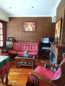 sala de estar con sofá rojo y chimenea en Casa a 2 cuadras de la playa en Necochea