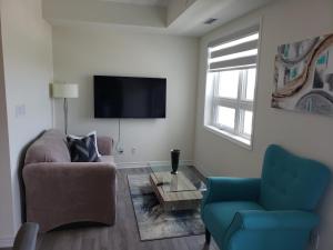 a living room with two chairs and a flat screen tv at Luxurious Condo Apartment 2BRs-1BAs-1Office with free parking in Brampton
