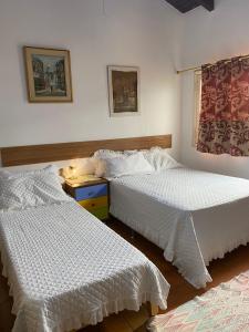 a bedroom with two beds with white sheets and a window at RESIDENCIA-UNIV in Ciudad del Este