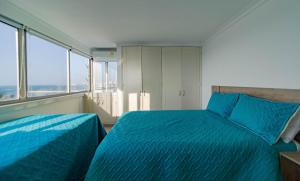 una camera con due letti blu e ampie finestre di Casa Tartaruga a Cartagena de Indias