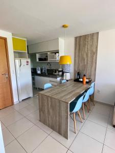 una cocina con una gran mesa de madera y sillas azules en Flat Beira Mar - Carneiros Beach Resort en Tamandaré