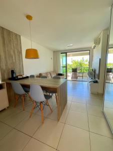 塔曼達雷的住宿－Flat Beira Mar - Carneiros Beach Resort，厨房以及带木桌和椅子的客厅。