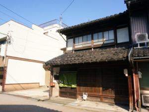 un edificio blanco con una puerta delante en （一棟貸切）町家体験ゲストハウス「ほんまちの家」〜高岡市の伝統的な古民家～, en Yokota