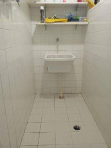 La salle de bains est pourvue de carrelage blanc et d'un lavabo. dans l'établissement Apartamento em Salvador, à Salvador