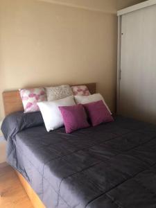 a bed with purple and white pillows on it at Departamento Villa crespo I in Buenos Aires