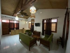 Balinese Villa Syariah في سيكوبانغْ: غرفة معيشة مع كراسي خضراء ومروحة سقف