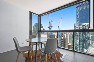 a dining room with a table and chairs and a large window at 37F Brisbane CBD Apartment with City Views and Pool in Brisbane