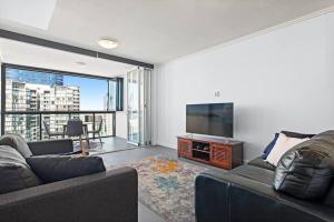a living room with a couch and a flat screen tv at 37F Brisbane CBD Apartment with City Views and Pool in Brisbane
