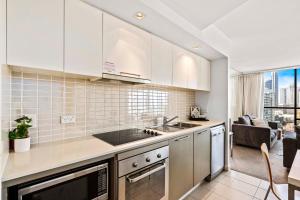 uma cozinha com armários brancos e vista para uma sala de estar em Ocean Views! - 2 Bedroom 2 Bathroom - Privately Managed em Gold Coast