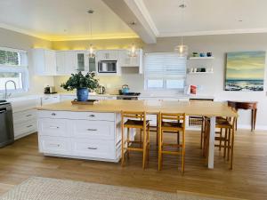 uma cozinha com armários brancos e uma mesa e cadeiras em Seapearl Oceanfront Villa and Cottage em Hermanus