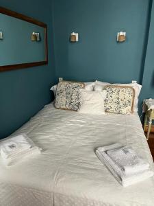 uma cama grande com lençóis brancos e almofadas em GABY'S HOME em Buenos Aires
