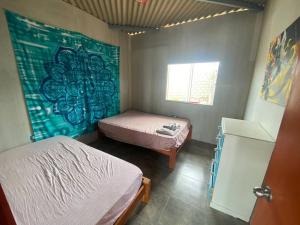 a bedroom with two beds and a painting on the wall at Casa Colan La Molina in Paita