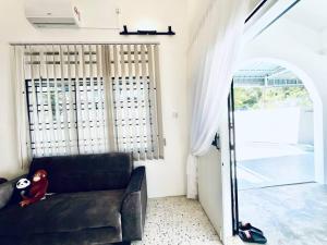 ein Wohnzimmer mit einem schwarzen Sofa und einem Fenster in der Unterkunft Gioia2Home 5 mins to Taiping/Kamunting in Taiping