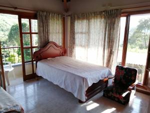 a bedroom with a bed and a chair and windows at Finca villa carolina, eje cafetero in La Floresta