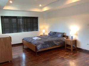 een slaapkamer met een bed en twee lampen op twee tafels bij แกรนด์ฮิลล์ เฮาส์ Grandhill house in Hua Hin