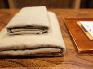 a stack of towels sitting on a wooden table at （一棟貸切）町家体験ゲストハウス「ほんまちの家」〜高岡市の伝統的な古民家～ in Yokota