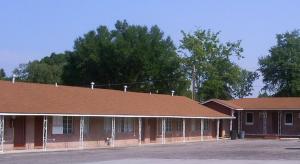 a brown building with a brown roof and trees at Crestview Inn in Crestview