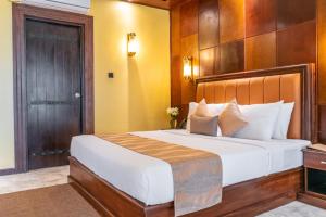 a bedroom with a large bed with a wooden headboard at Birds Resort Hambantota in Hambantota