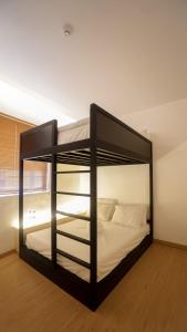 a black bunk bed in a room with white sheets at ManukabyHavis Boutique Hotel in Nagoya