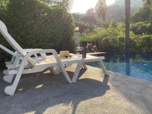 een witte tafel en stoel naast een zwembad bij แกรนด์ฮิลล์ เฮาส์ Grandhill house in Hua Hin