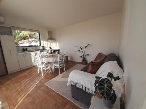 The Tiny Abode في Snells Beach: غرفة معيشة مع أريكة وطاولة