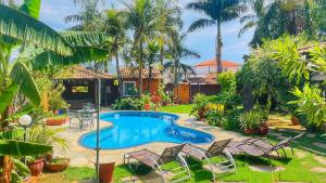 a pool in a yard with chairs and a house at Pousada Verdes Encantos in Pirenópolis