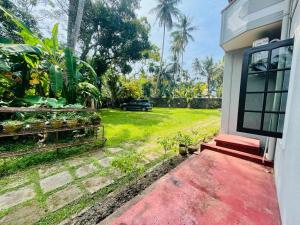 a house with a red porch and a yard at Galle Side HomeStay in Galle
