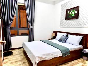 バオロクにあるHotel Hoa Nắngのベッドルーム1室(白いシーツと青いカーテンのベッド1台付)