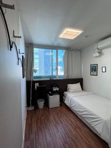 sypialnia z łóżkiem, biurkiem i oknem w obiekcie Ekonomy Haeundae Hostel w Pusanie