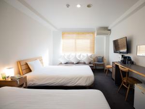 鹿児島市にあるYou Style Hotel MARINEのベッド2台とデスクが備わるホテルルームです。