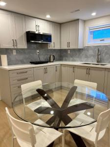 a kitchen with a glass table and white cabinets at BRAND NEW lower home with EXCLUSIVE Bathroom in Toronto