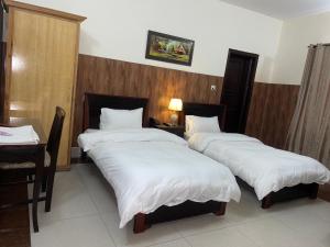 a bedroom with three beds with white sheets at Crown Castle Peshawar in Peshawar