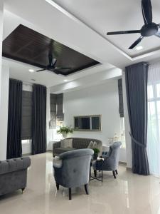 a living room with a ceiling fan and chairs at elyssa_homes in Kota Bharu