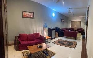 a living room with red chairs and a tv at Crown Castle Peshawar in Peshawar