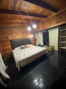 1 dormitorio con 1 cama en una habitación de madera en PIEDRAS PRECIOSAS en Villa Gesell