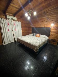 a bedroom with a bed in a wooden cabin at PIEDRAS PRECIOSAS in Villa Gesell