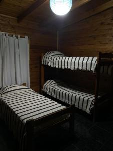 a room with three beds in a wooden cabin at PIEDRAS PRECIOSAS in Villa Gesell