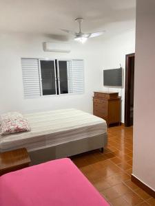 1 dormitorio con 1 cama y TV de pantalla plana en Casa de praia, en Guarujá