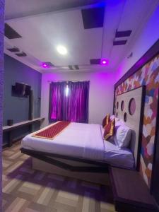 Ooty OWLS NEST INN في أوتي: غرفة نوم بسرير كبير مع اضاءة ارجوانية
