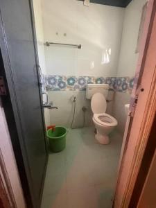 uma casa de banho com um WC e um balde verde em Ooty OWLS NEST INN em Ooty