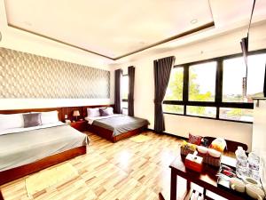 バオロクにあるHotel Hoa Nắngのベッド2台とテーブルが備わるホテルルームです。