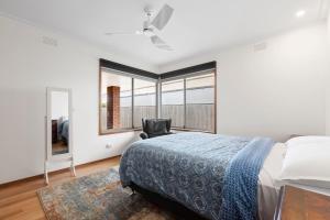 a bedroom with a bed and a chair and a window at Lonnie Getaway in Point Lonsdale