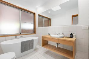 a white bathroom with a tub and a sink at Lonnie Getaway in Point Lonsdale +11 photos