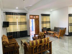 uma sala de estar com sofás e cadeiras e uma televisão em Holiday Resort em Trincomalee
